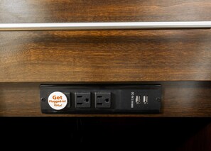A wooden drawer with a black electrical outlet box containing a plug-in socket, two USB ports, and a label that reads "Get Plugged-In! Keep Rooftop."