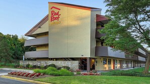 A Red Roof Plus hotel with a stone facade, multiple balconies, and a landscaped front yard. - Red Roof Inn PLUS+ Washington DC - Oxon Hill (Oxon Hill)