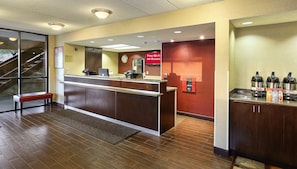 A hotel reception area with a reception desk, a clock, a sign indicating free Wi-Fi, a water dispenser, and a coffee station. - Red Roof Inn PLUS+ Washington DC - Oxon Hill (Oxon Hill)
