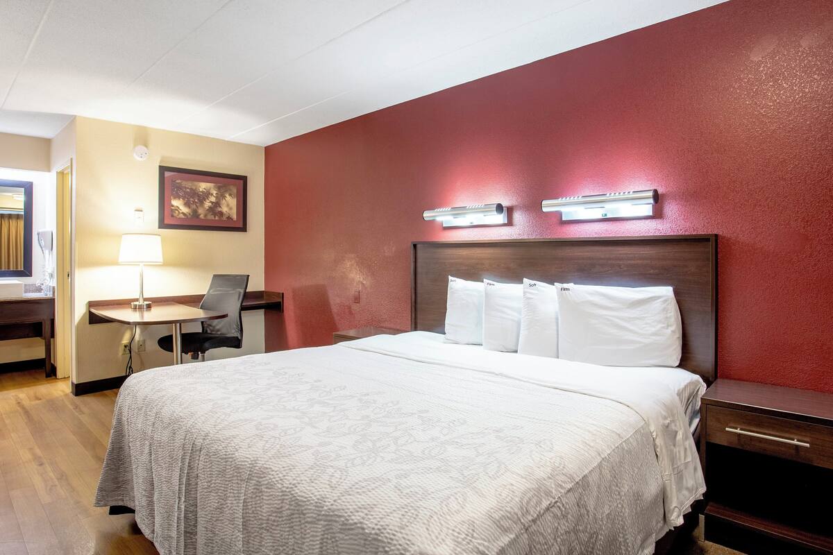 A hotel room with a bed, a desk, and a chair.
