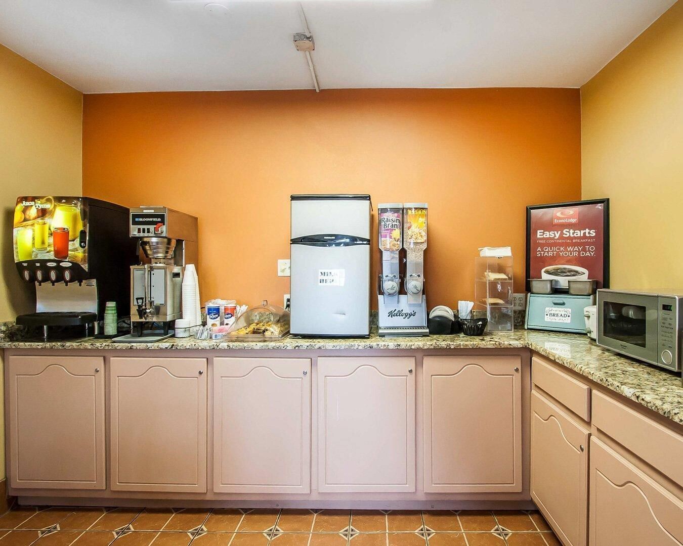 A kitchenette with a coffee machine, a refrigerator, a microwave, and a bread maker.