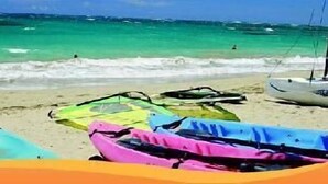 Une plage avec des kayaks aux couleurs vives et un voilier.