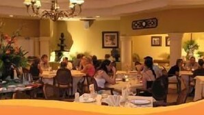 Un restaurant doté de nombreuses tables et chaises, d’un lustre et de plantes décoratives.