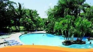 Une piscine entourée d’une végétation luxuriante et de palmiers.