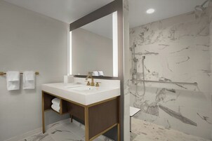 Un baño moderno con un espejo grande, un lavamanos y una ducha.