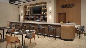A modern bar area with a curved counter, bar stools, and a seating area with tables and chairs.