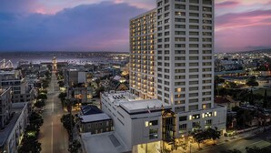 A high-rise hotel with multiple floors, a prominent entrance, and a view of the surrounding cityscape and waterfront.
