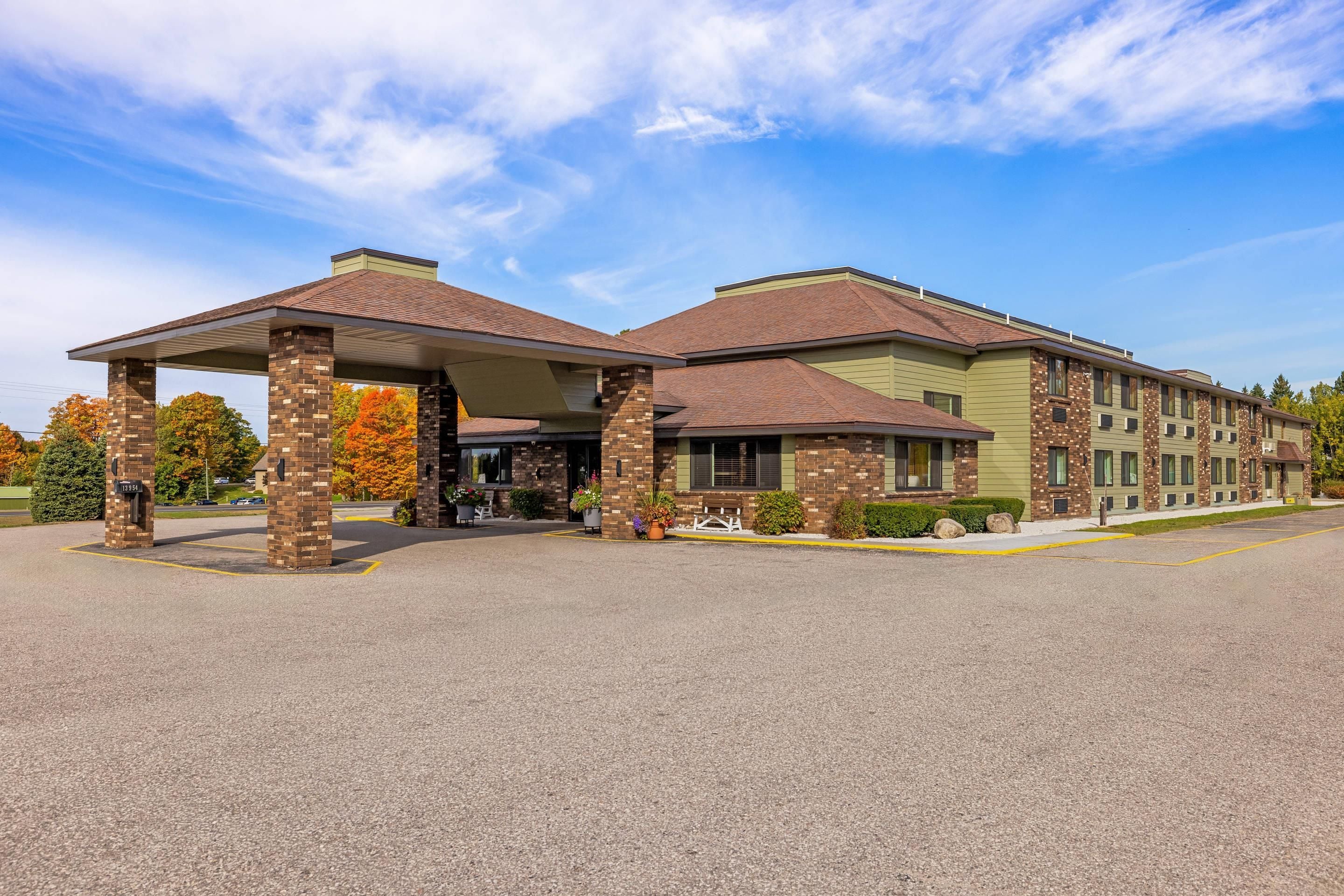 A hotel with a covered entrance, brick pillars, and a green facade.