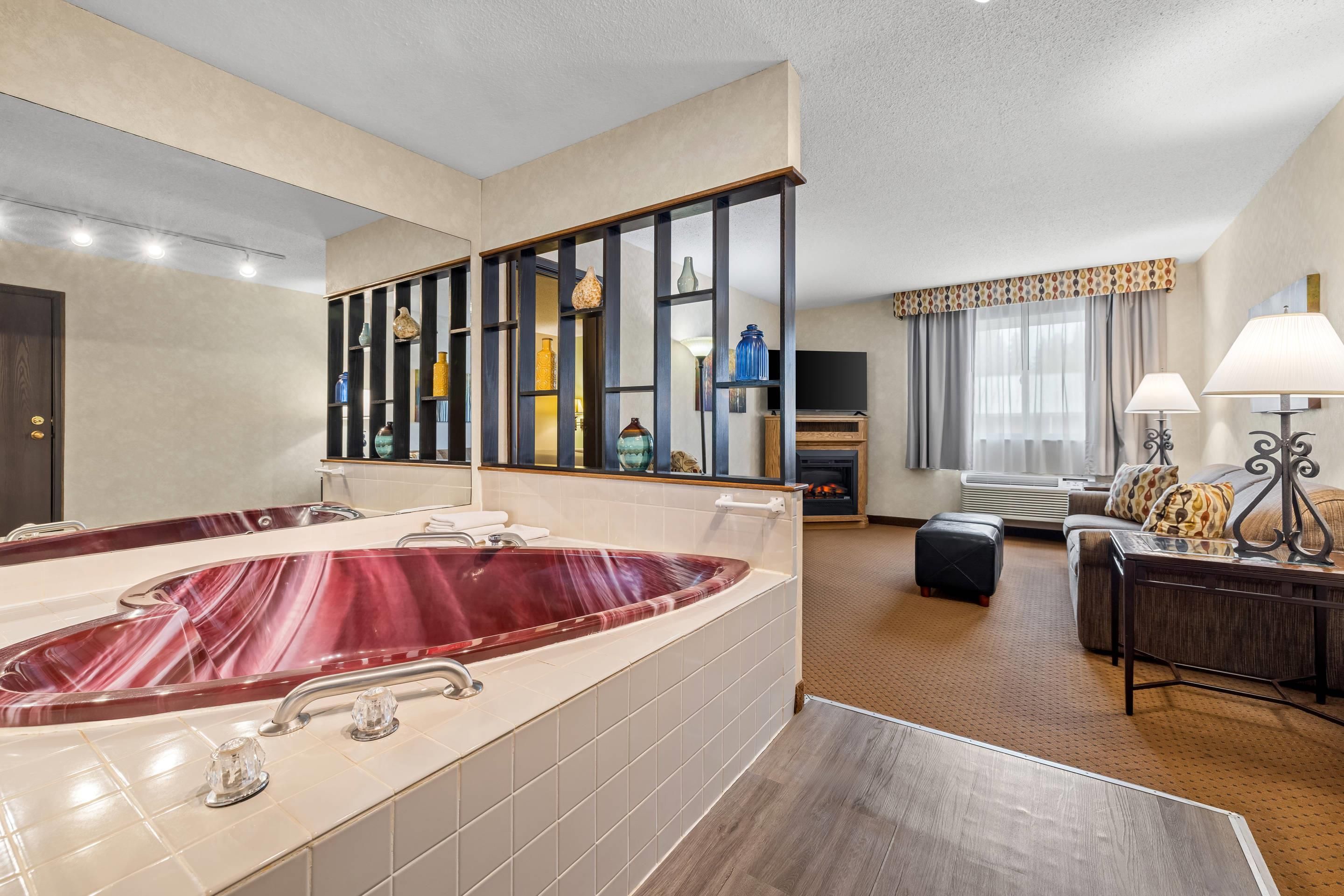 A hotel bathroom with a large bathtub, a mirror, and a vanity with shelves.