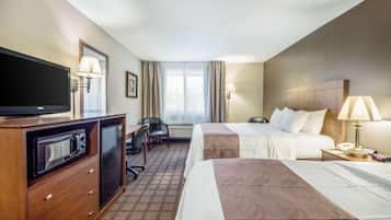 A hotel room with two beds, a TV, a desk, and a chair.