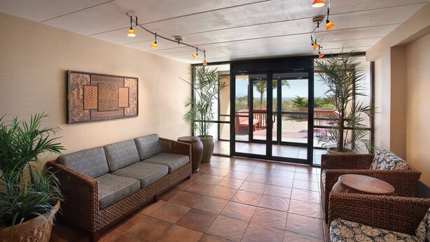 A spacious indoor area with a wicker sofa, wicker chairs, and potted plants. - Quality Inn Oceanfront (Ocean City)
