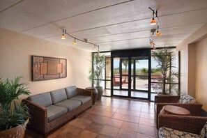 A spacious indoor area with a wicker sofa, wicker chairs, and potted plants. - Quality Inn Oceanfront (Ocean City)