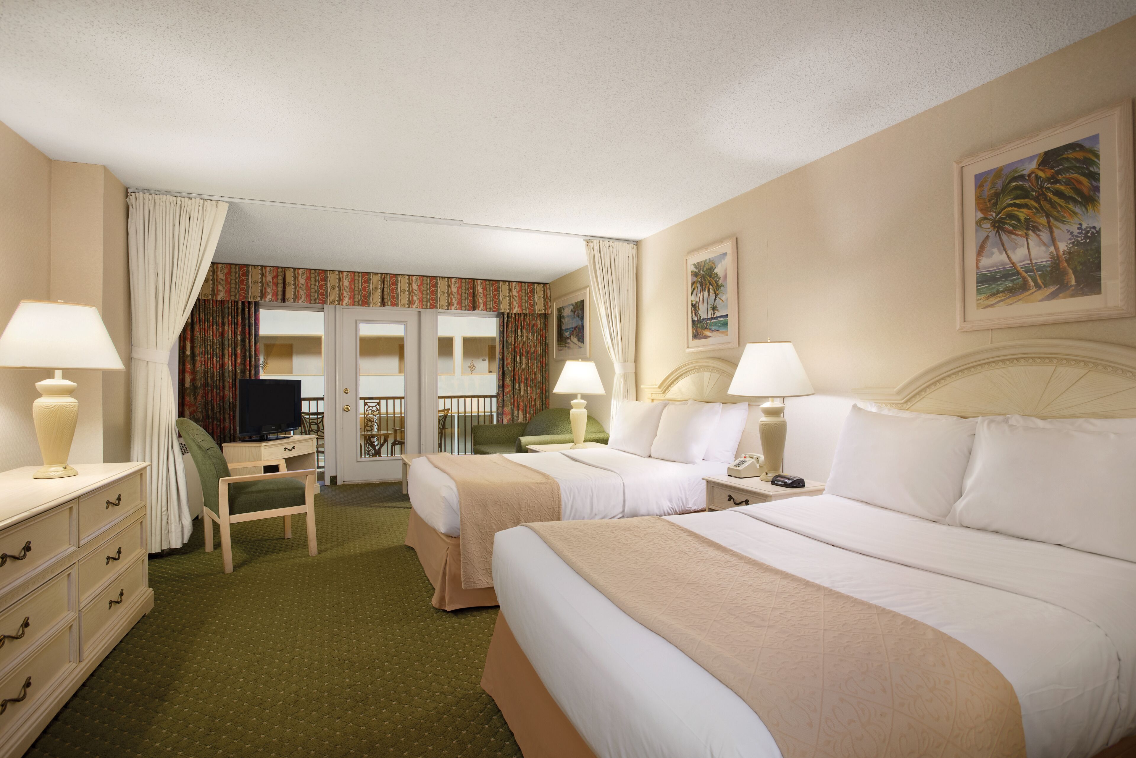 A hotel room with two beds, a desk, a chair, and a television.