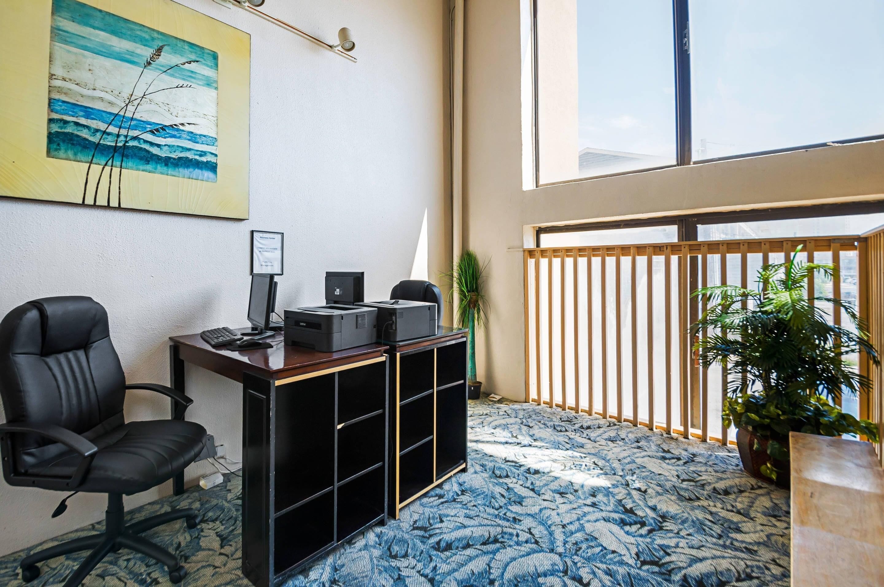 A room with a desk, chair, computer, printer, and a large window.
