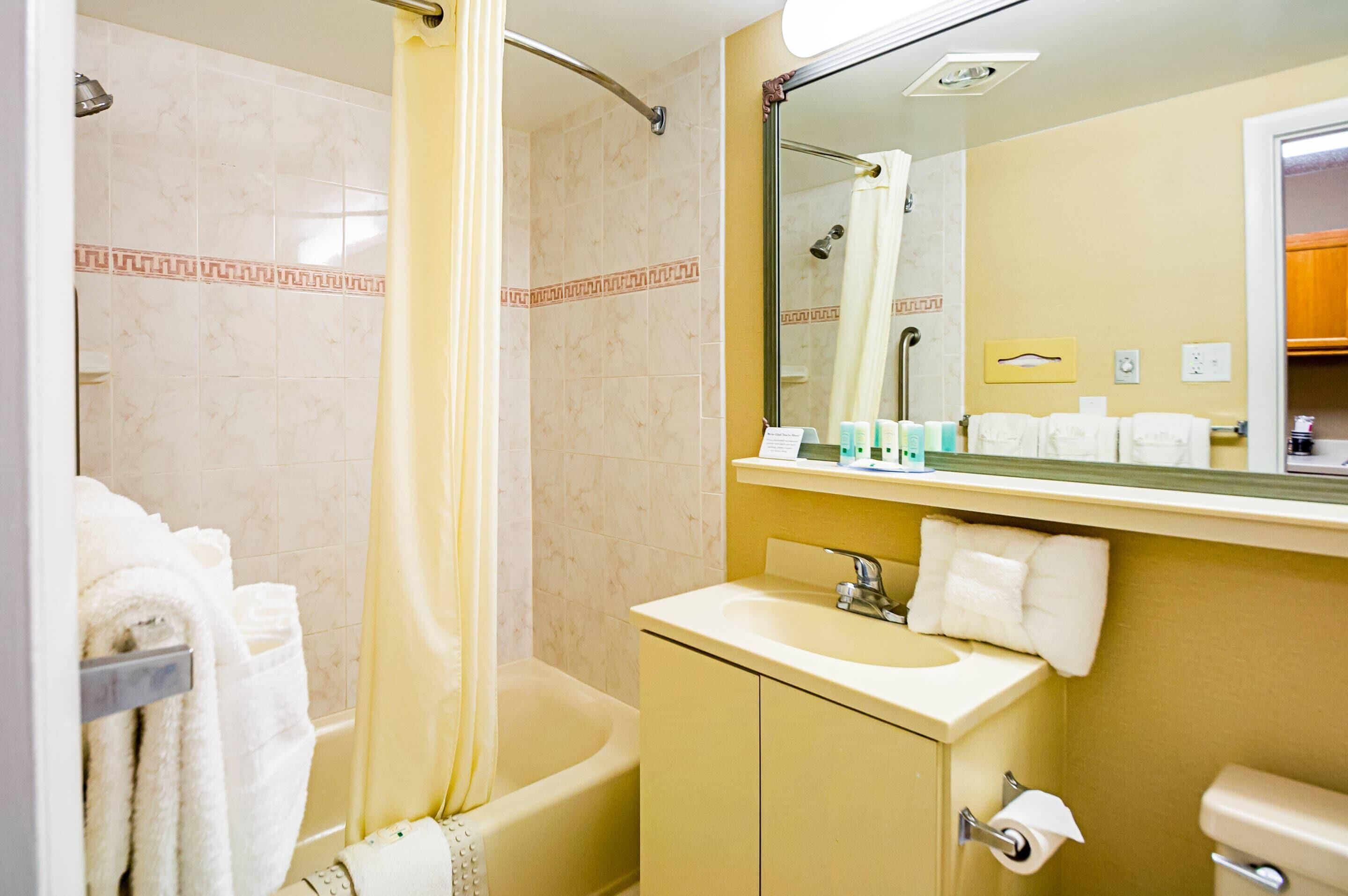 A bathroom with a bathtub, a sink, a mirror, and a shower curtain.