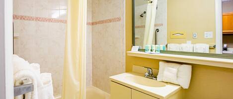 A bathroom with a bathtub, a sink, a mirror, and a shower curtain.