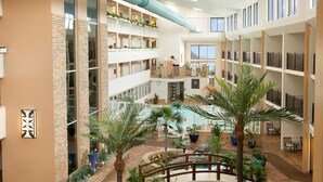 A multi-level atrium with a central water feature, surrounded by planters and seating areas. - Quality Inn Oceanfront (Ocean City)