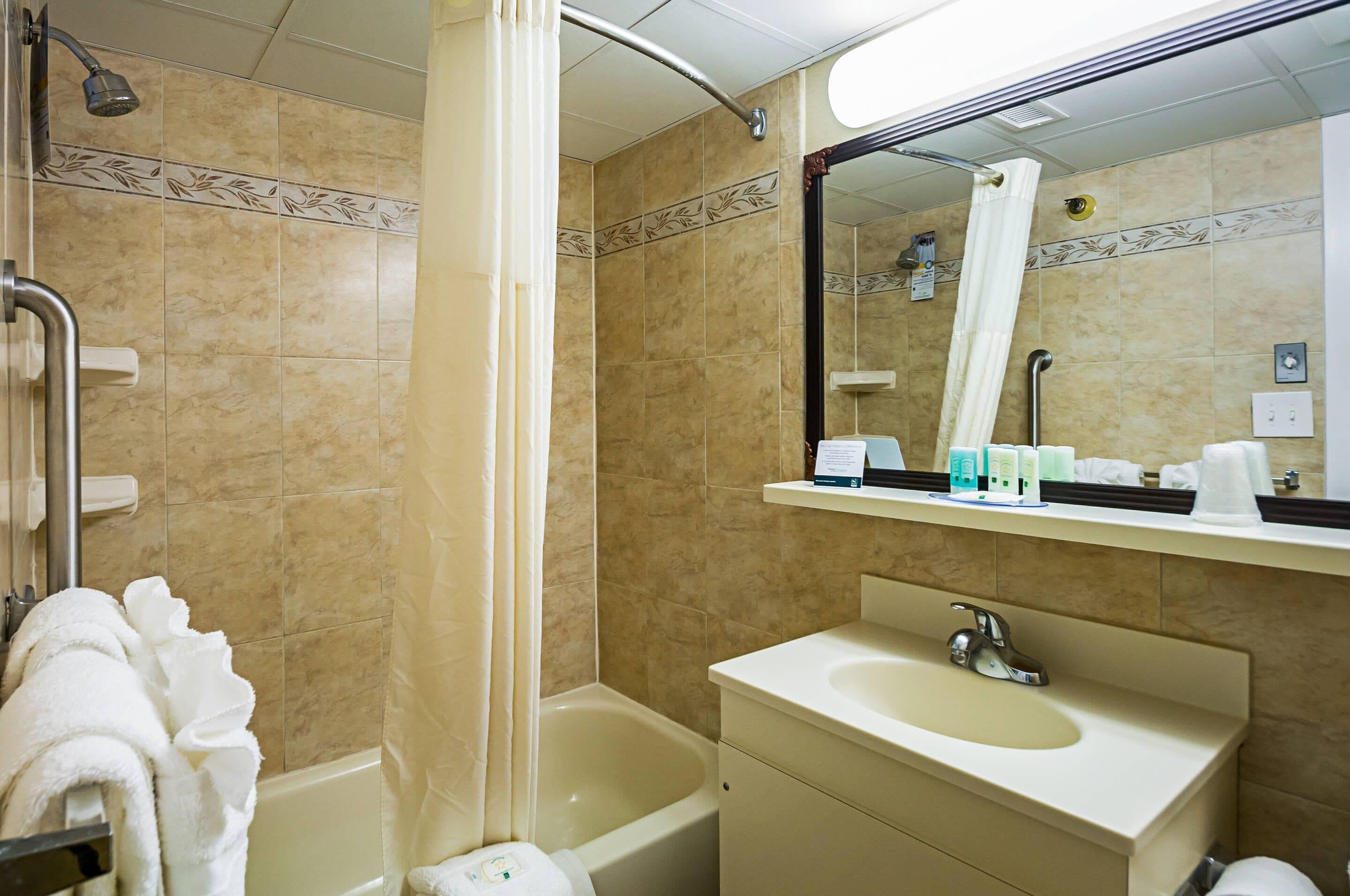 A bathroom with a bathtub, a sink, a mirror, and a shower.