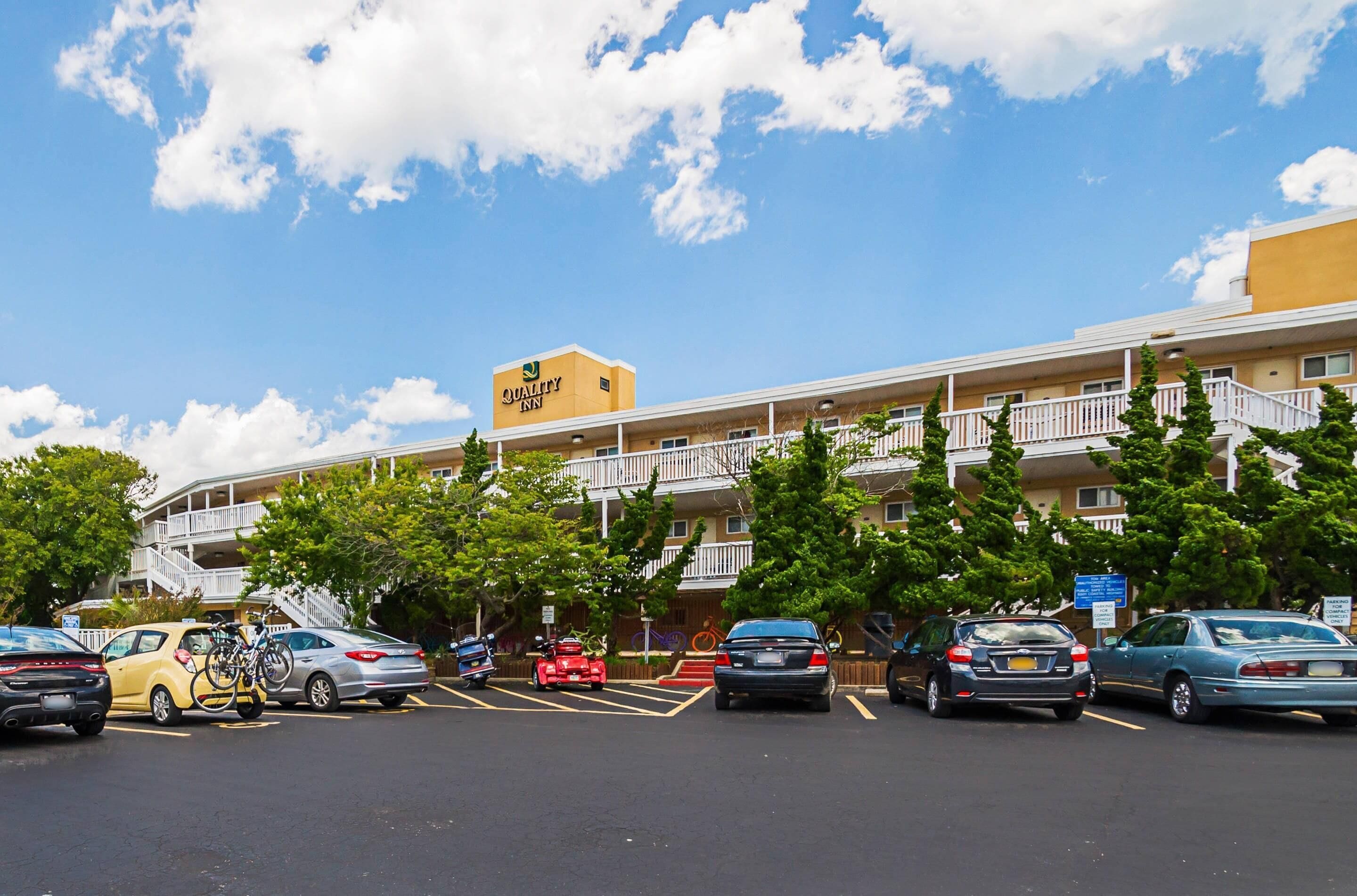 A hotel with a yellow exterior, multiple floors, and a balcony on the upper levels.
