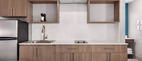 Una cocina moderna con armarios de madera, un refrigerador de acero inoxidable, un lavamanos y una cafetera.