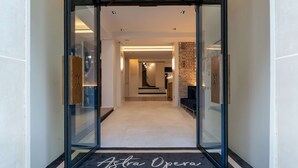 A hotel entrance with a modern design, featuring a glass door, a carpet with the hotel's name, and a staircase leading to the interior. - Hôtel Astra Opéra - Astotel (Paris)