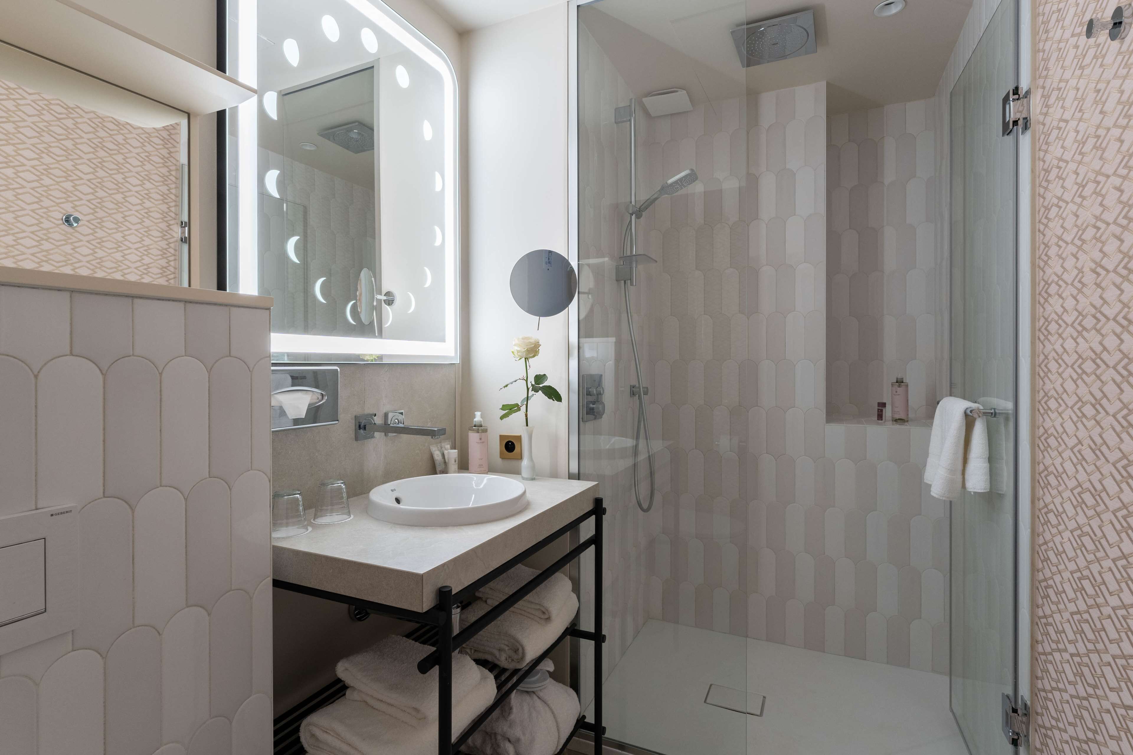 Une salle de bain moderne avec une douche à parois de verre, un meuble-lavabo et un grand miroir.