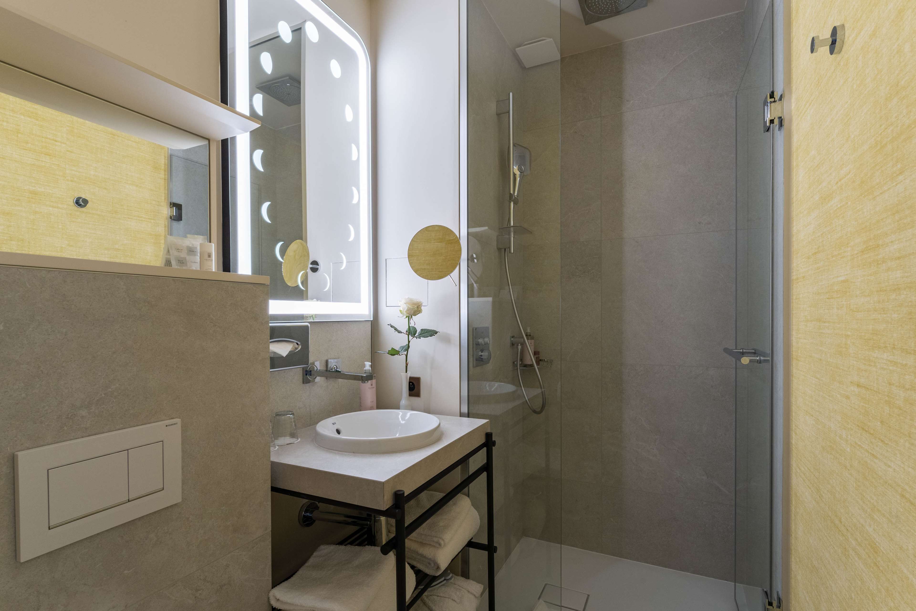 Un baño moderno con tocador, espejo y ducha.
