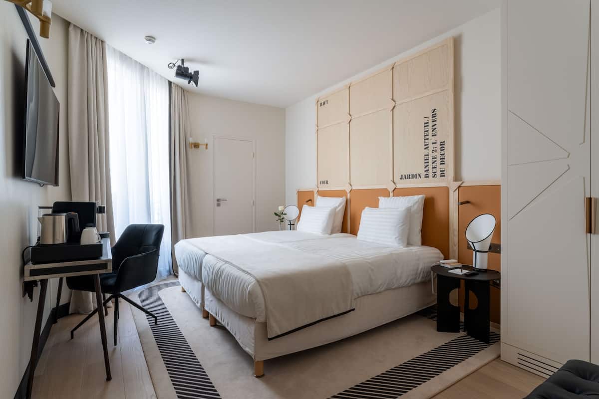Una habitación de hotel moderna con una cama grande, un escritorio con una silla, un televisor y un armario.