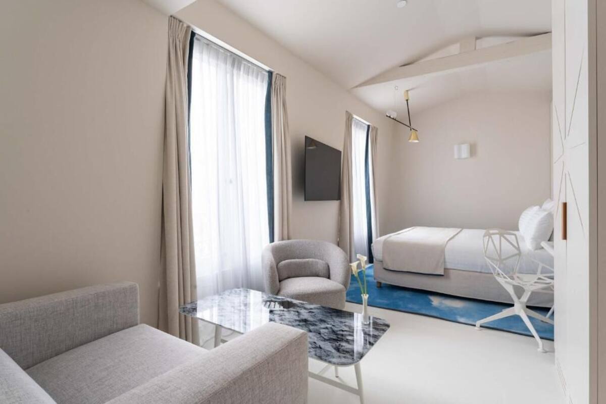 Una habitación de hotel moderna con sofá, una mesita, cama y televisión.