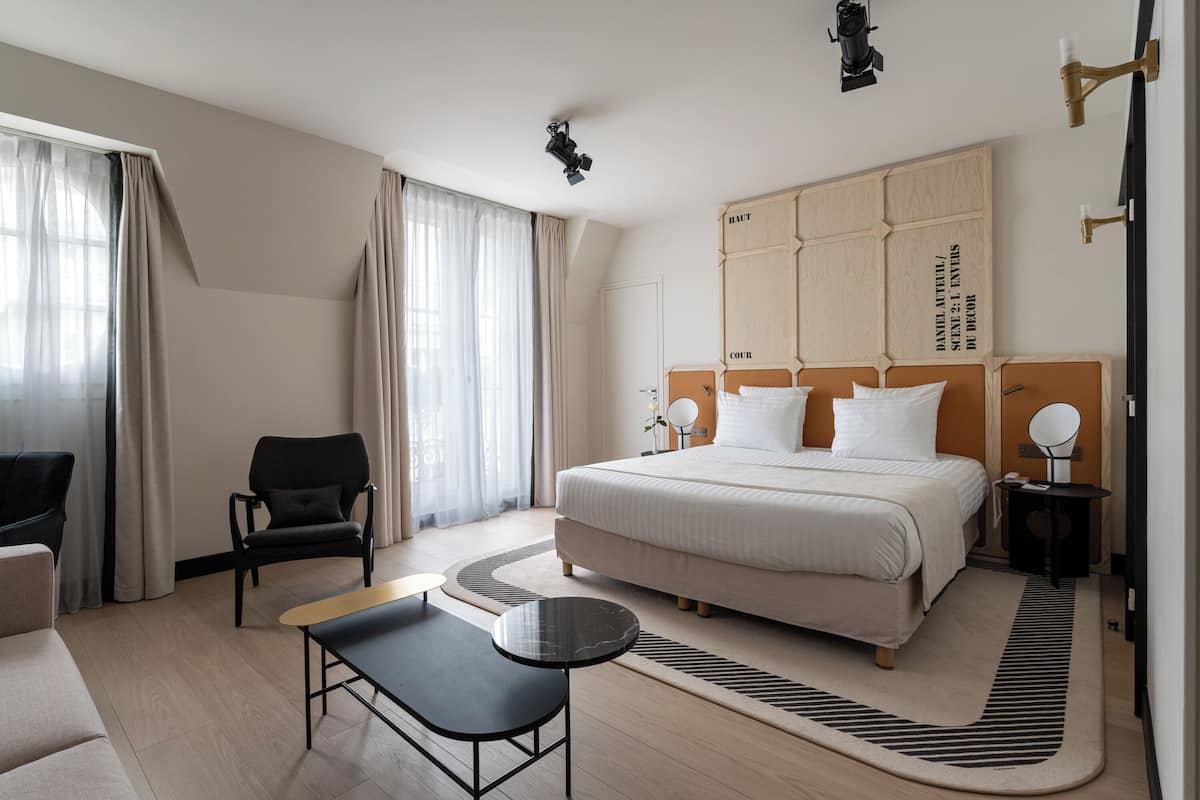 Una habitación de hotel moderna con una cama grande, un escritorio, una silla y un sofá.