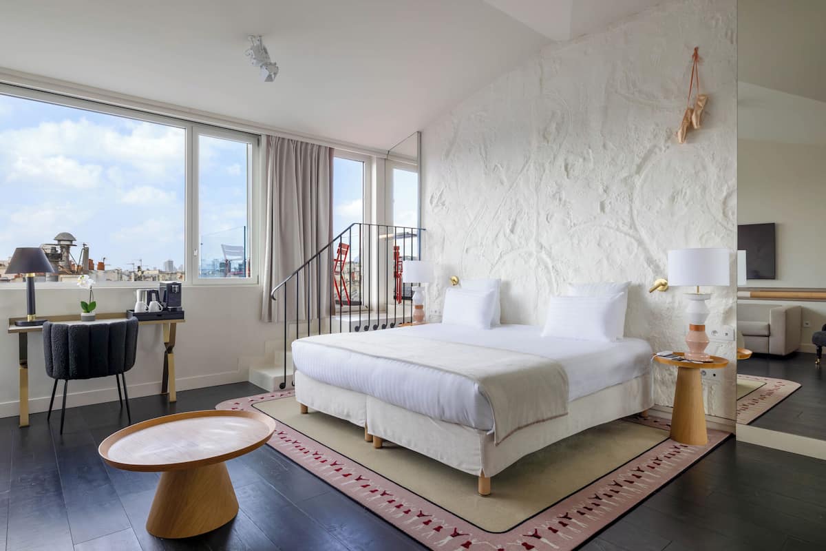 Una habitación de hotel moderna con una cama grande, un escritorio y vistas a la ciudad.