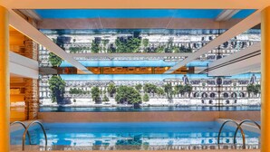 A swimming pool with a cityscape view through a glass wall. - Hôtel Astra Opéra - Astotel (Paris)