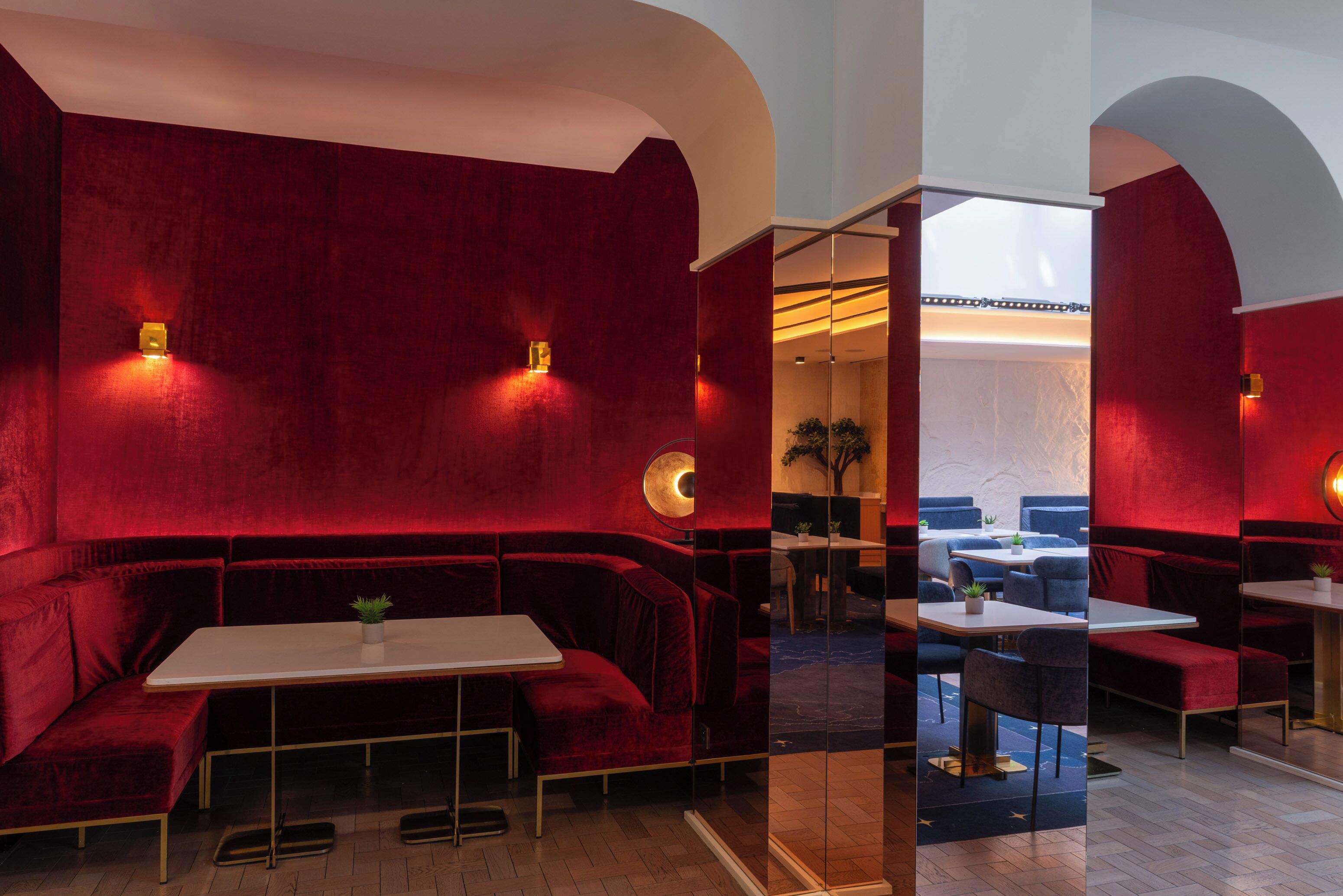 Un espacio lounge de terciopelo rojo con una mesa blanca, asientos e iluminación de pared.