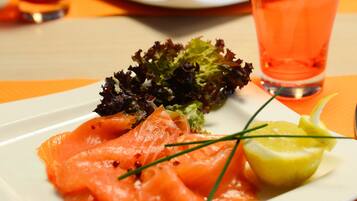 A plate of smoked salmon with a side salad and a glass of orange juice.