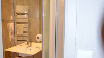 Un baño moderno con cabina de ducha de vidrio, un lavabo con espejo y un perchero para toallas.