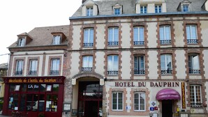 Un bâtiment historique, reconnaissable à son panneau bien visible indiquant « HÔTEL DU DAUPHIN », qui présente un style architectural européen classique, avec de nombreuses fenêtres et une façade en briques.