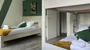 Une chambre avec deux lits superposés, un mur vert et un tableau.