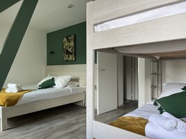 Quarto com duas beliches, uma parede verde e um quadro.