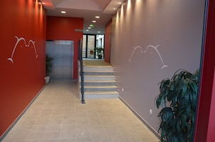 Um lobby de hotel moderno com parede vermelha, escada e balcão de recepção.