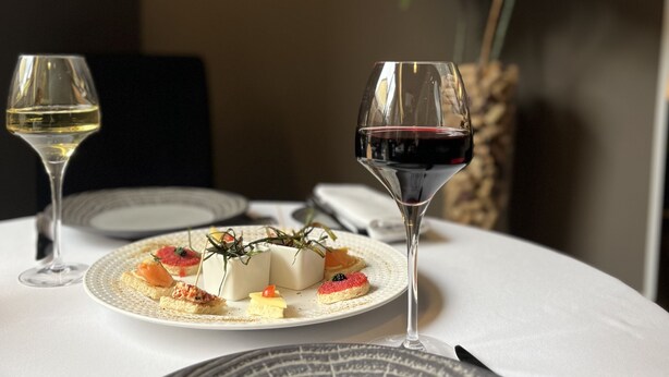 Une table dressée avec des assiettes, des verres et un vase rempli de fleurs.