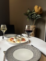 Uma mesa posta com pratos, copos e um vaso de flores.