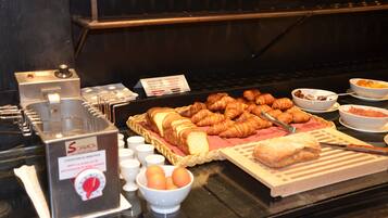 A buffet with croissants, bread, and bowls of food.