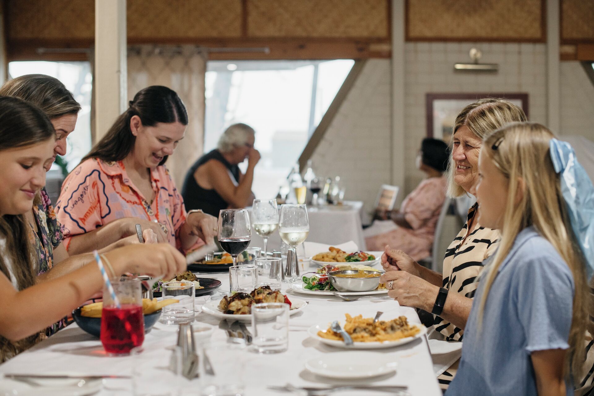 Un grupo de personas cenando en una mesa con varios platos y copas de vino.