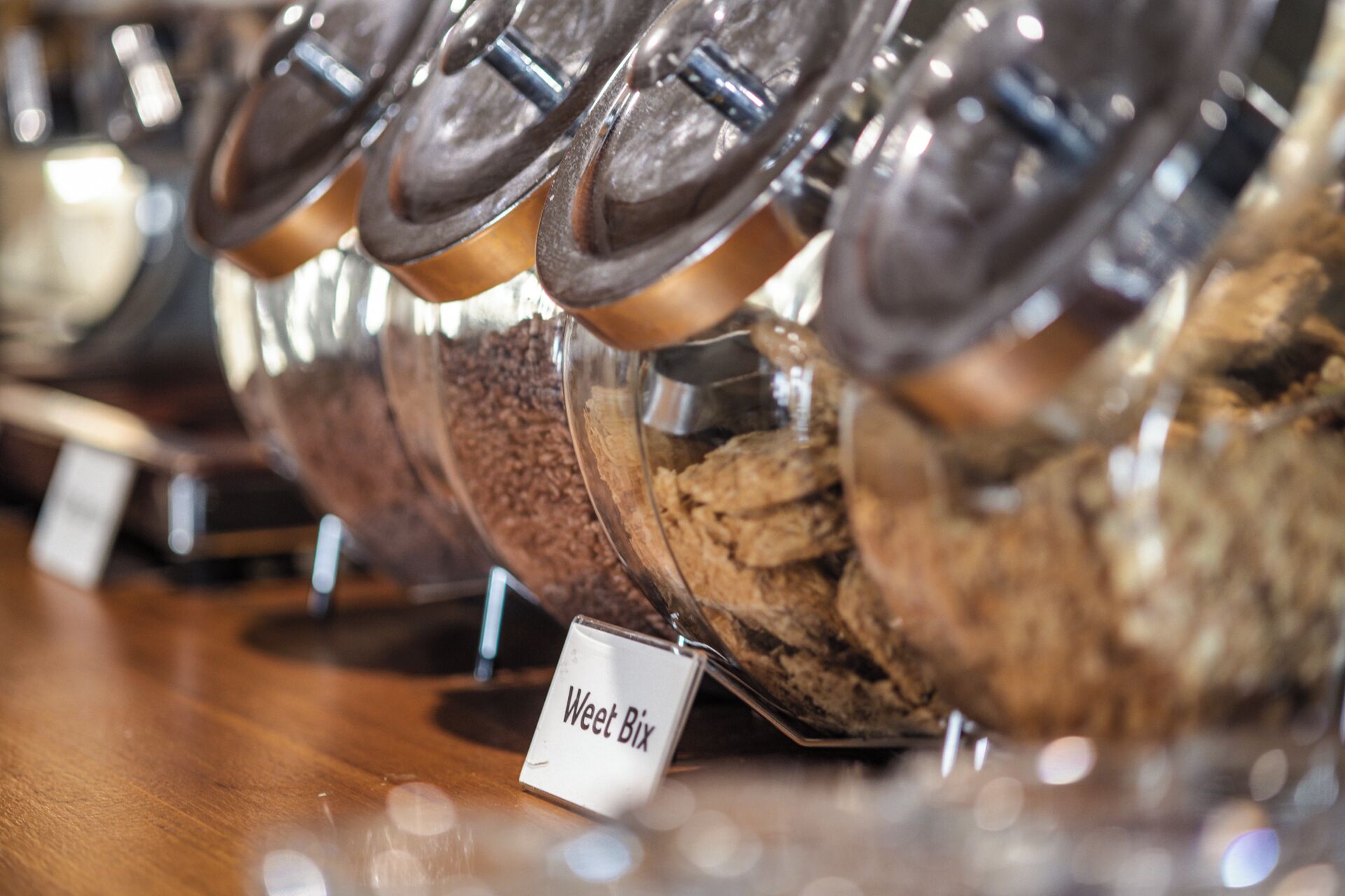 A display of various types of coffee beans in clear containers, each labeled with a name tag.