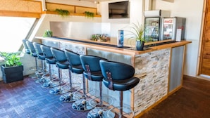 A bar area with a stone wall, black bar stools, and a Coca-Cola refrigerator. - Hospitality Carnarvon, SureStay Collection by Best Western (South Carnarvon)
