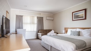 A hotel room with a bed, a desk, a chair, a TV, and a window with curtains. - Hospitality Carnarvon, SureStay Collection by Best Western (South Carnarvon)