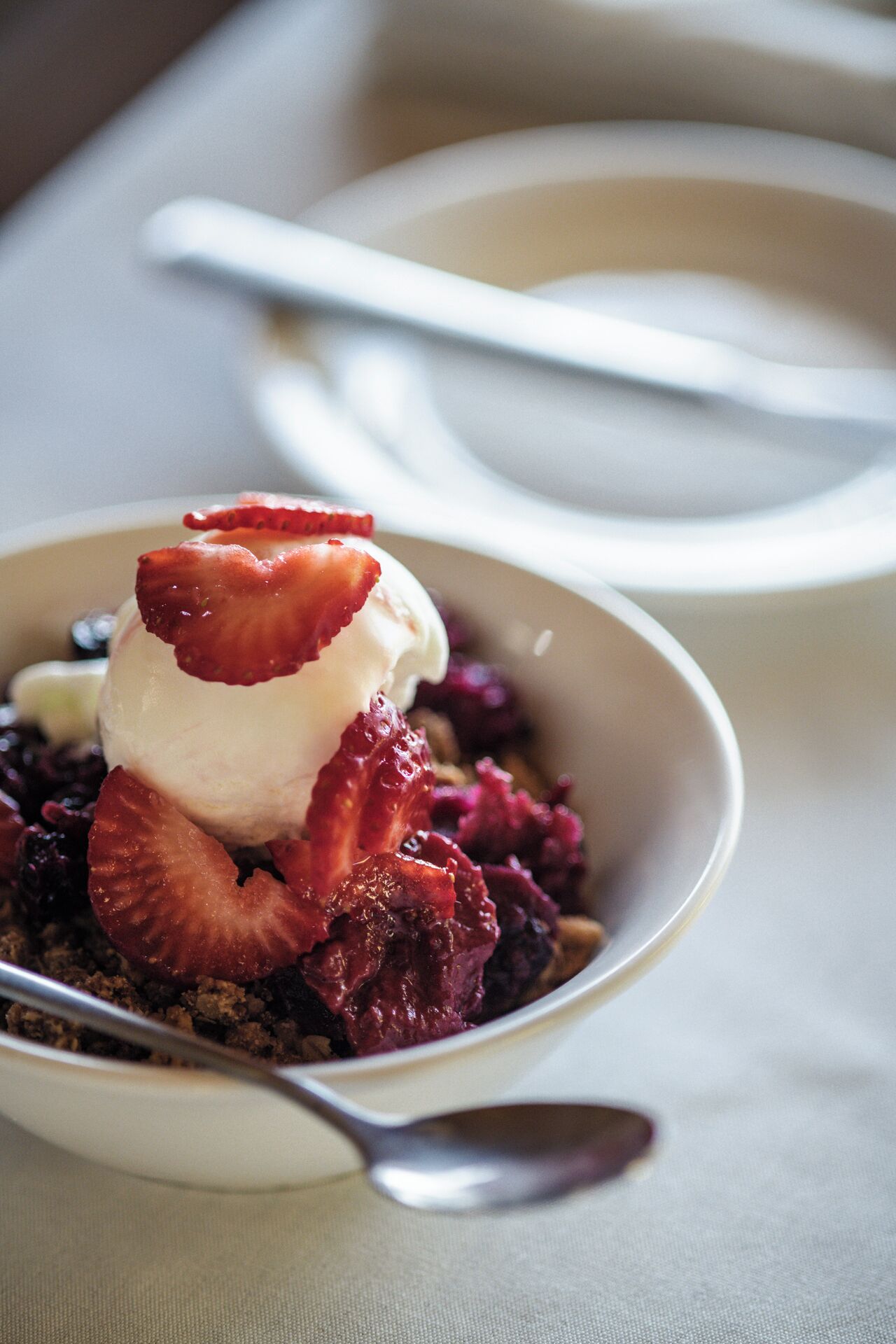Una coppa di dessert con fragole e gelato.