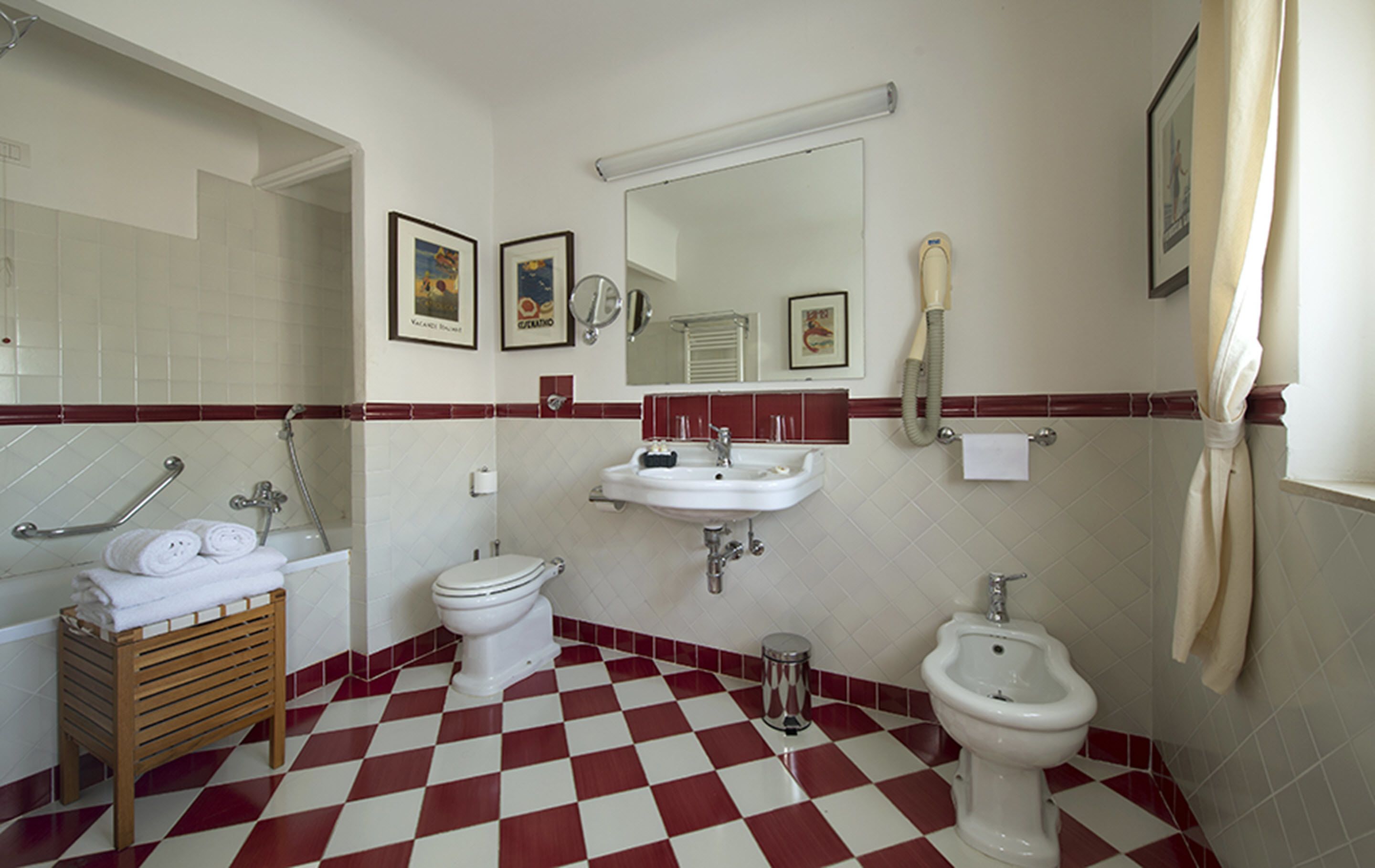 A bathroom with a checkered floor, a sink, a toilet, a bidet, and a shower area.
