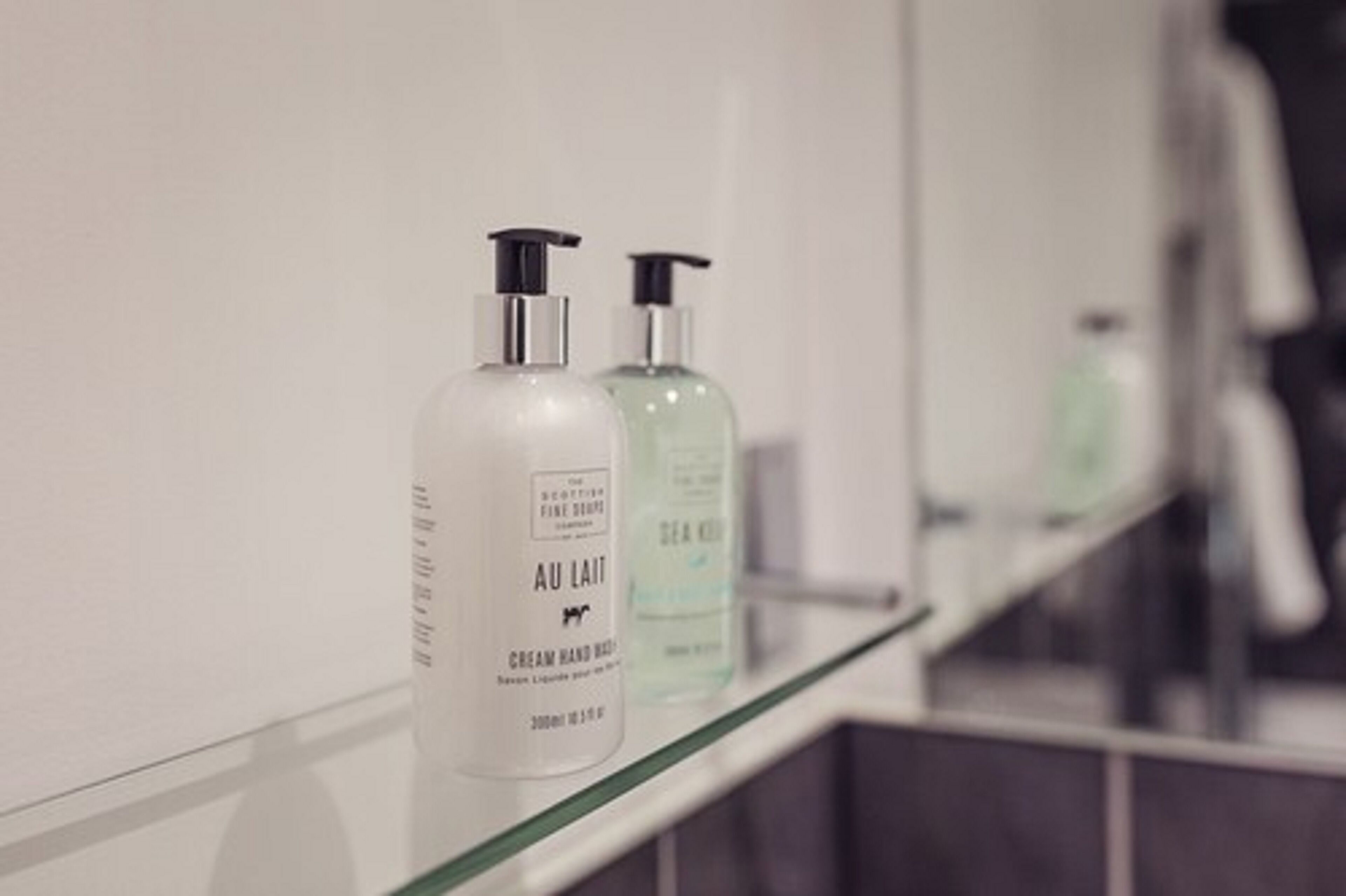 Deux flacons de produits de soins pour la peau sont posés sur une étagère dans la salle de bain.