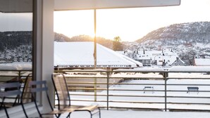 A balcony with metal railings and a view of a snow-covered town and mountains. - Scandic Bergen City (Bergen)